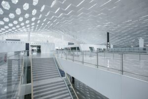 Modern airport interior with geometric ceiling and glass railings, highlighting a spacious and bright design.