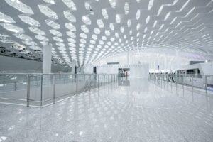 Modern architectural space with perforated ceiling and polished reflective floor.