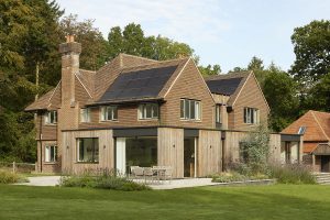 Contemporary eco-home with wooden exterior, solar panels, and serene nature surroundings.