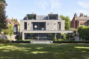 Modern two-storey house with terrace, large windows, and a beautifully landscaped garden.