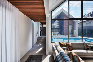 Modern living area with pool view by Hobbs Jamieson Architecture.