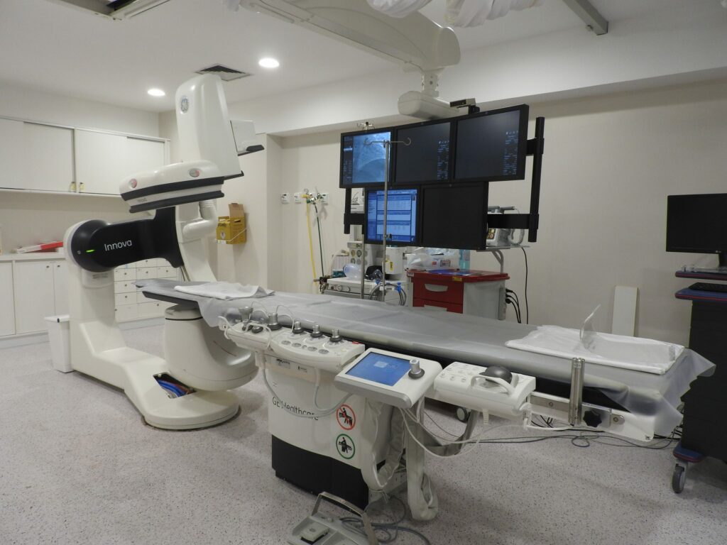 Modern medical imaging room with advanced C-arm machine and multi-screen setup for radiological procedures.