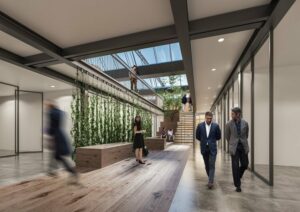 Modern office corridor with glass ceiling, greenery, and people moving and interacting.
