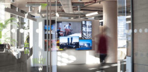 Modern open-plan office with glass partitions, natural light, and minimalist furniture.