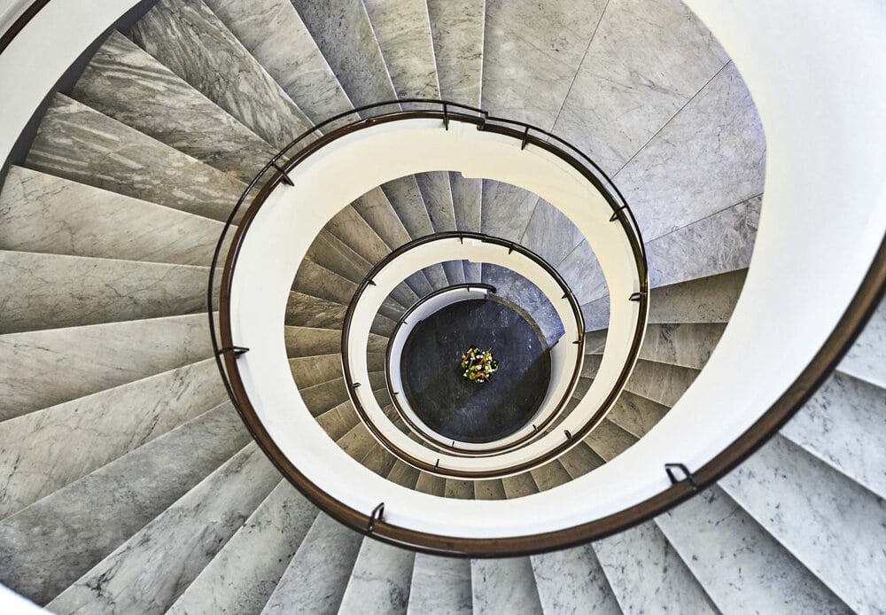 Top-down view of an elegant, modern spiral staircase with sleek lines and monochromatic tones.