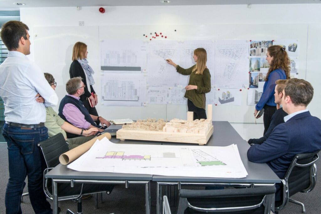 Team discussing architectural plans in a modern office setting.