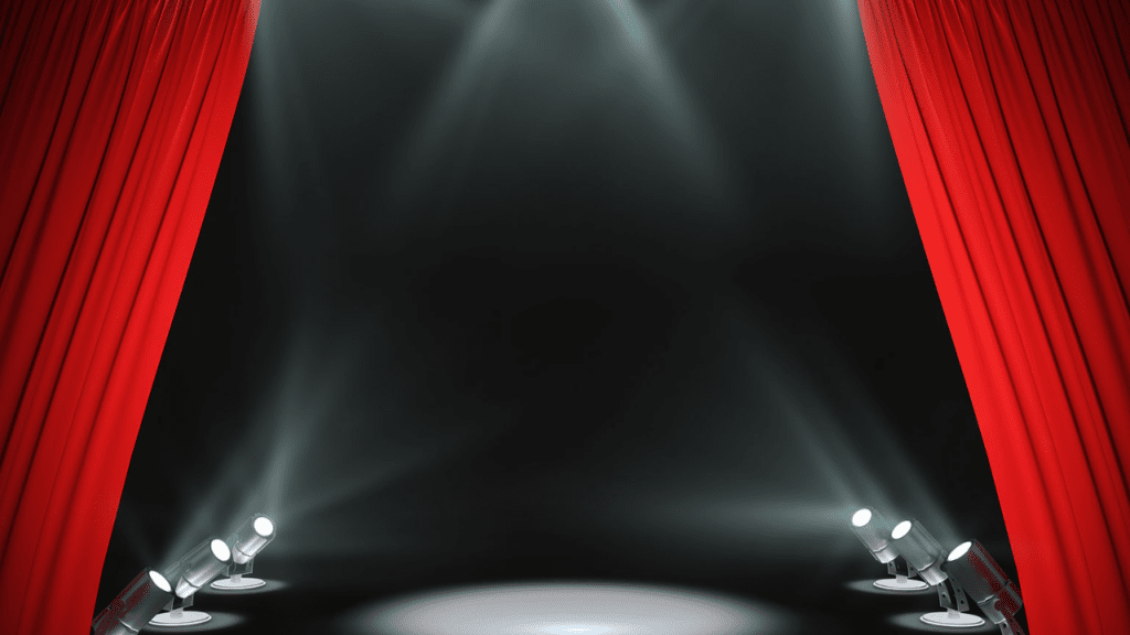 Theatre stage with red curtains and spotlights awaiting performance.