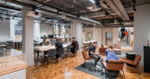Modern open-plan office with parquet flooring, exposed beams, and collaborative workspaces.