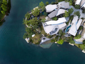 Modern waterfront residences with sleek architecture, lush greenery, and tranquil water views.