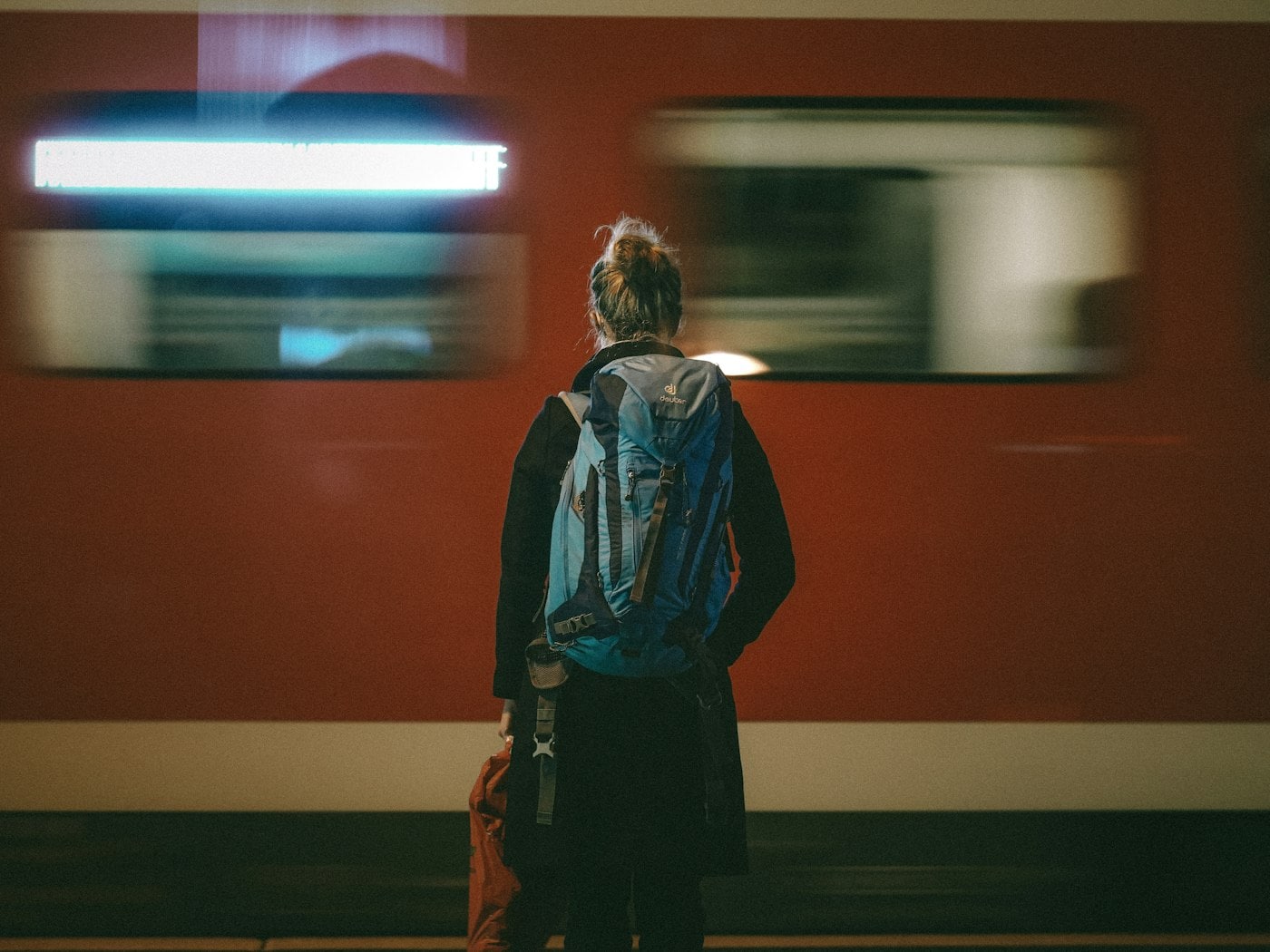 Person with a backpack watching a train, representing travel before starting architecture work
